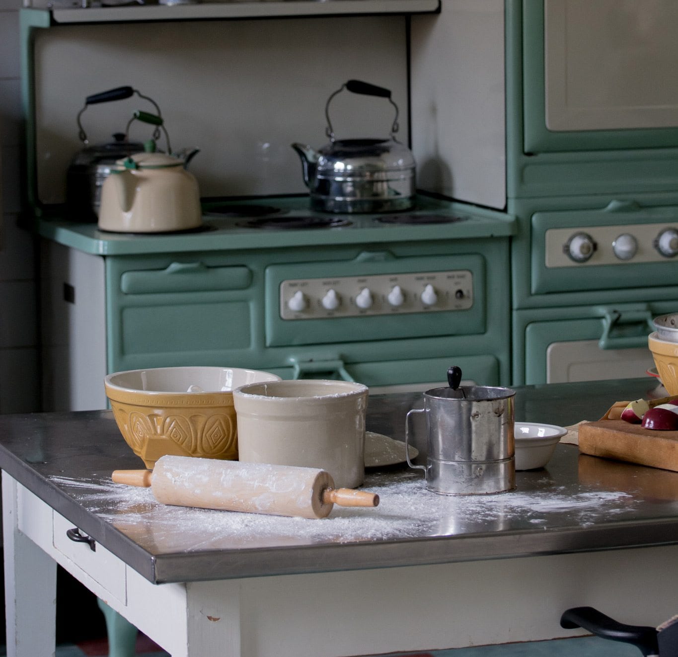 Pizza roller, bowls and flour on a table in a kitchen