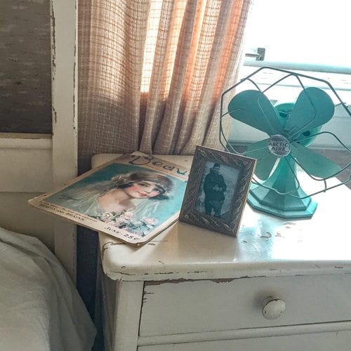 Old magazine, photograph and fan on a white dresser