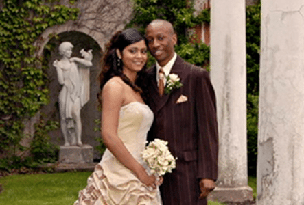 A man and woman in wedding attire pose near the Parkwood Estate