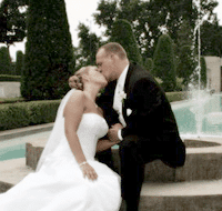 Married couple kissing by the fountain on their wedding day